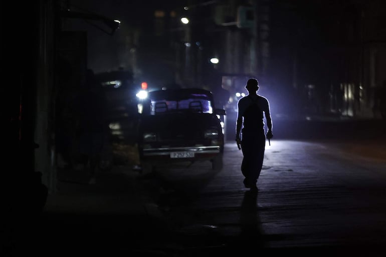 Una persona caminando por una calle sin luz durante un apagón en La Habana (Cuba).