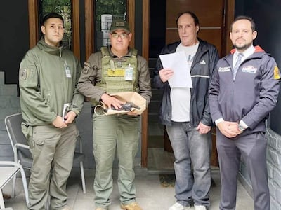 Luciano Pereira Castelo con hoja en mano, rodeado de militares y abogado, en un entorno formal.