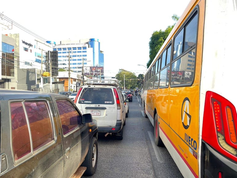 Tráfico intenso en una calle de Asunción con varios vehículos, incluyendo un autobús amarillo de Iveco.