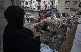 Una mujer observa los trabajos de búsqueda de cuerpos entre escombros de edificios destruidos en Jan Yunis, en el sur de la Franja de Gaza.