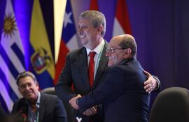 El presidente del Tribunal Superior de Justicia Electoral de Paraguay, Jaime Bestard (i), y el magistrado del Consejo Nacional Electoral de Colombia, Álvaro Echeverry, se saludan en la apertura de la XXII Conferencia de la Asociación de Organismos Electorales de América del Sur este martes, en Asunción (Paraguay).