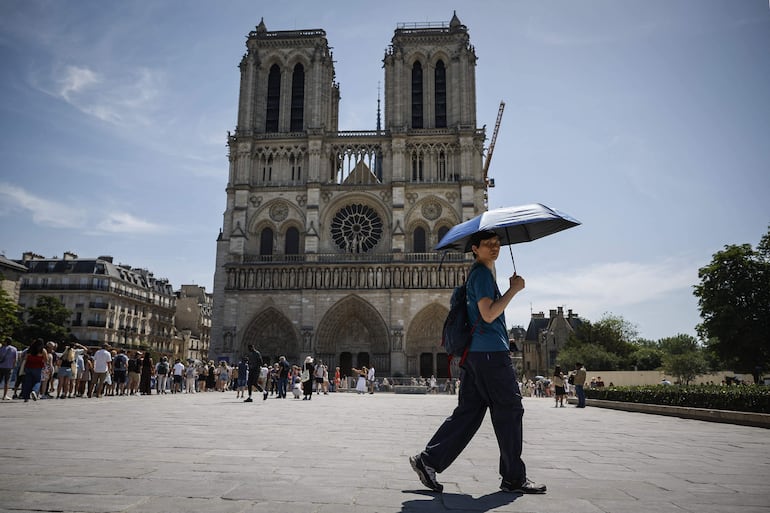 Un turista se protege del sol bajo un paraguas frente a la catedral de Notre-Dame en París, mientras una ola de calor temprana y récord azota amplias zonas de Europa occidental el 28 de mayo de 2026.