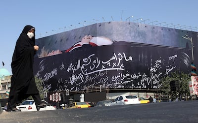Una mujer iraní con velo camina junto a una enorme valla publicitaria antiamericana que muestra al presidente de EE. UU., Donald Trump, en un ataúd, acompañada de una frase en persa que dice "Matamos a Trump", exhibida en la plaza Enghelab de Teherán, Irán.