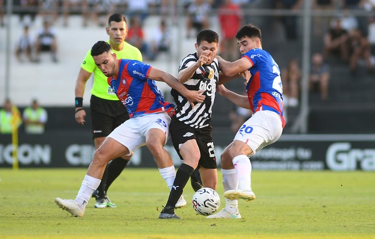 Hernesto Caballero (c), futbolista de Libertad, disputa el balón con Fabrizio Peralta (i) y Wilder Viera (d), jugadores de Cerro Porteño, en un partido del torneo Clausura 2023 dle fútbol paraguayo en La Huerta, en Asunción.
