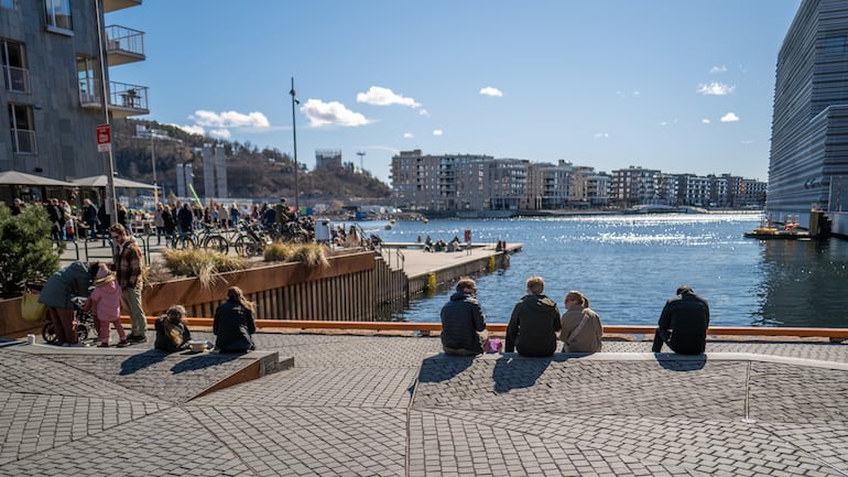 Personas relajadas sentadas junto al mar en Sørenga, Oslo, Noruega.