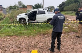 Un policía de Homicidios frente a la camioneta acribillada por sicarios en Pedro Juan Caballero.