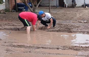 Vecinos del barrio Villa Policial de Pilar intentan arreglar un caño roto de la ESSAP que inunda las calles y patios de las casas desde hace una semana, según denunciaron.