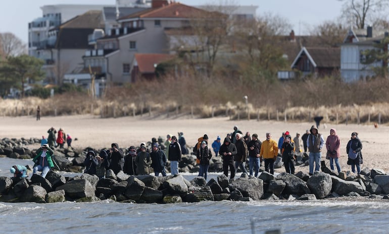 Espectadores observan a una ballena varada en las aguas del mar Báltico, cerca del puerto de Niendorf, en Timmendorfer Strand, Alemania, el 26 de marzo de 2026. 