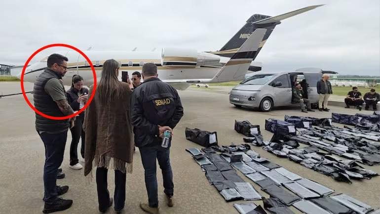 Gustavo Sandoval conversando con la fiscala Ingrid Cubilla y Cristian Amarilla, en el aeropuerto, con avión y furgoneta al fondo.