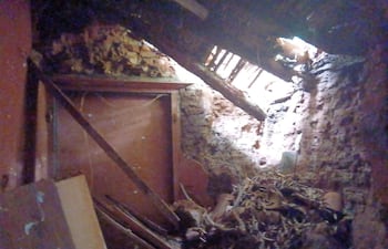 Interior deteriorado con paredes de ladrillo expuesto y vigas de madera dañadas.