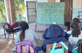 Estudiantes de la escuela Nueva Asunción de Chacó'i dan clases bajo un árbol y comparten la pizarra entre varios grados.