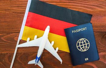 Imagen ilustrativa: una bandera de Alemania con un pequeño avión y un pasaporte.