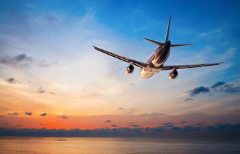 Avión sobrevolando el mar al atardecer durante maniobra de aproximación a un aeropuerto. Foto: Iryna Rasko/Shutterstock facilitada por Journalistic.org.
