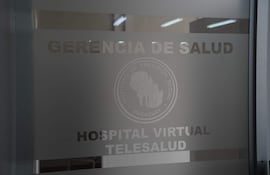 Puerta de vidrio de oficina con inscripciones del IPS, 'Hospital Virtual Telesalud' y logo del Instituto de Previsión Social.