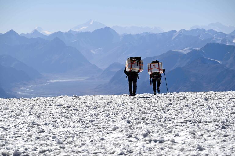 Dos miembros de la expedición 'Pamir-Ice-Memory' descienden el glaciar de Pamir, llevando muestras de núcleos de hielo en una nevera portátil hacia el campamento base, en Kon Chukurbashi, Tayikistán oriental, el 24 de septiembre de 2025.