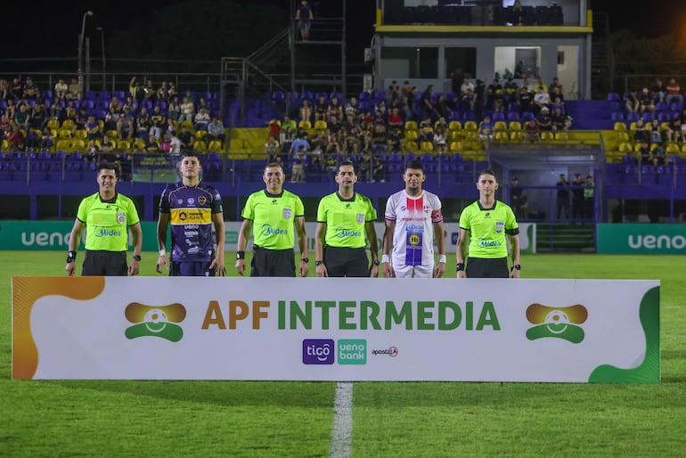 La terna arbitral en el campo de juego junto a los capitanes de ambos equipos.
