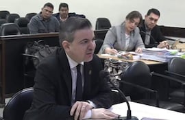 Dr. José Duarte Penayo en traje oscuro habla frente a un micrófono, otros cuatro escuchan atentamente en una sala de audiencias.
