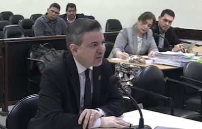 Dr. José Duarte Penayo en traje oscuro habla frente a un micrófono, otros cuatro escuchan atentamente en una sala de audiencias.