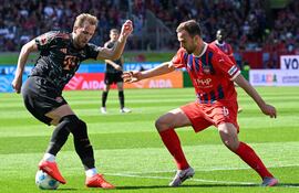 Bayern Munich's English forward #09 Harry Kane (L) and Heidenheim's German midfielder #05 Benedikt Gimber vie for the ball during the German first division Bundesliga football match between Heidenheim and Bayern Munich in Heidenheim, southern Germany on April 19, 2025. (Photo by THOMAS KIENZLE / AFP) / DFL REGULATIONS PROHIBIT ANY USE OF PHOTOGRAPHS AS IMAGE SEQUENCES AND/OR QUASI-VIDEO