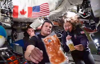 Esta captura de pantalla tomada de una transmisión en vivo de la NASA muestra a los astronautas de la misión Artemis II (de izquierda a derecha) el comandante de la NASA Reid Wiseman, el especialista de misión de la Agencia Espacial Canadiense Jeremy Hansen y la especialista de misión de la NASA Christina Koch durante una breve demostración de la comida que consumen en el espacio.