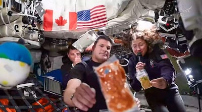 Esta captura de pantalla tomada de una transmisión en vivo de la NASA muestra a los astronautas de la misión Artemis II (de izquierda a derecha) el comandante de la NASA Reid Wiseman, el especialista de misión de la Agencia Espacial Canadiense Jeremy Hansen y la especialista de misión de la NASA Christina Koch durante una breve demostración de la comida que consumen en el espacio.