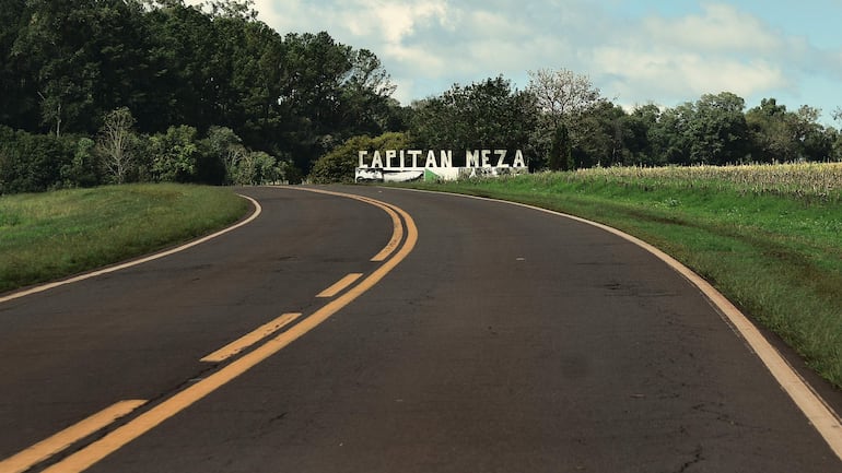 Camino en mal estado flanqueado por vegetación. Letrero de 'CAPITAN MEZA' visible a la derecha.