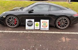 Porsche negro estacionado con carteles de Policía Federal y BPFRON en un entorno verde.