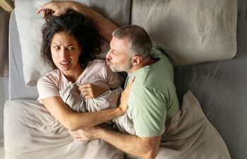 Pareja cansada en la cama, imagen ilustrativa.