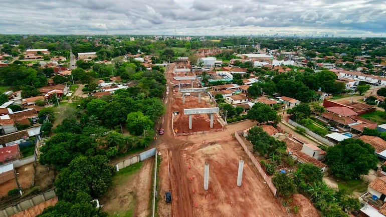 Vista aérea de obra en Luque con pilares de concreto y maquinarias de construcción en un entorno verde.