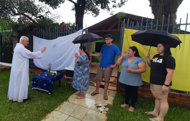 El sacerdote Tranquilo Monfroi imparte la bendición frente a una vivienda durante el recorrido procesional en el barrio Santa Ana.