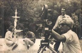 Fotografía tomada por Carlos Saguier que muestra a parte del equipo que trabajó en El Pueblo. En primer plano, Petit Goroso, asistente de cámara y mano derecha del director para lograr los mejores encuadres. En segundo plano, con la claqueta, Antonio Pecci, asistente de dirección. En tercer plano, Estela Lamar, entonces actriz del TPV, y Papo Díaz Peña, seleccionados para una producción televisiva. Jardín Botánico, hacia 1970-71. (Cortesía de Antonio Pecci.)