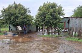 Hombre de pie con camiseta oscura y pantalones cortos sostiene una cámara en un paisaje inundado en Puerto Carrizal.