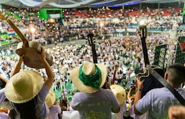 Jóvenes músicos con guitarras y sombreros de paja, participando en un festival musical en un ambiente festivo y lleno de energía.