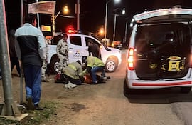 Dos hombres con chalecos amarillos asisten a un anciano en el suelo cerca de una ambulancia en la ruta PY06.