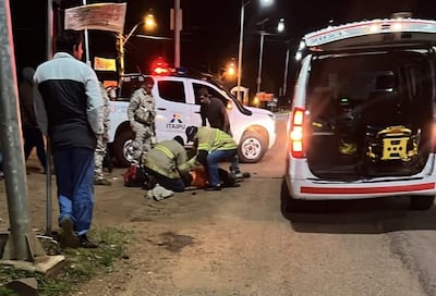 Dos hombres con chalecos amarillos asisten a un anciano en el suelo cerca de una ambulancia en la ruta PY06.