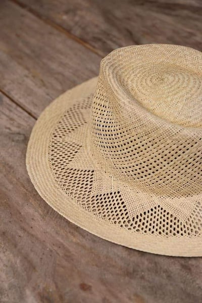 Sombrero de paja trenzado sobre madera, sin personas visibles ni elementos contextualizadores en la imagen.