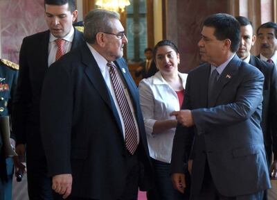 Horacio Cartes con blazer oscuro y corbata, conversando con Antonio Fretes en elegante ambiente gubernamental.