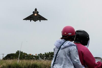Civiles observan el vuelo de un avión caza de la Fuerza Aérea de Taiwán, en la base de Hsinchu.