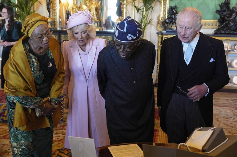 El rey Carlos III, el presidente de Nigeria, Bola Tinubu; la reina Camila y la primera dama de Nigeria, Oluremi Tinubu, observan una exposición especial de objetos de la Colección Real relacionados con Nigeria en el Salón Verde del Castillo de Windsor. (Aaron Chown / POOL / AFP)