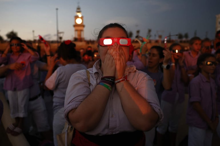 Personas reaccionan mientras observan el eclipse solar total desde el puerto de Tarragona, en el noreste de España, el 12 de agosto de 2026.
