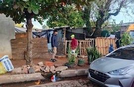 Tres personas en la calle: un hombre con chaqueta oscura, joven con abrigo rojo y gorra verde, y un niño en abrigo azul.