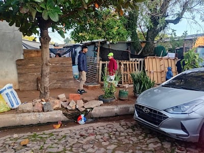 Tres personas en la calle: un hombre con chaqueta oscura, joven con abrigo rojo y gorra verde, y un niño en abrigo azul.