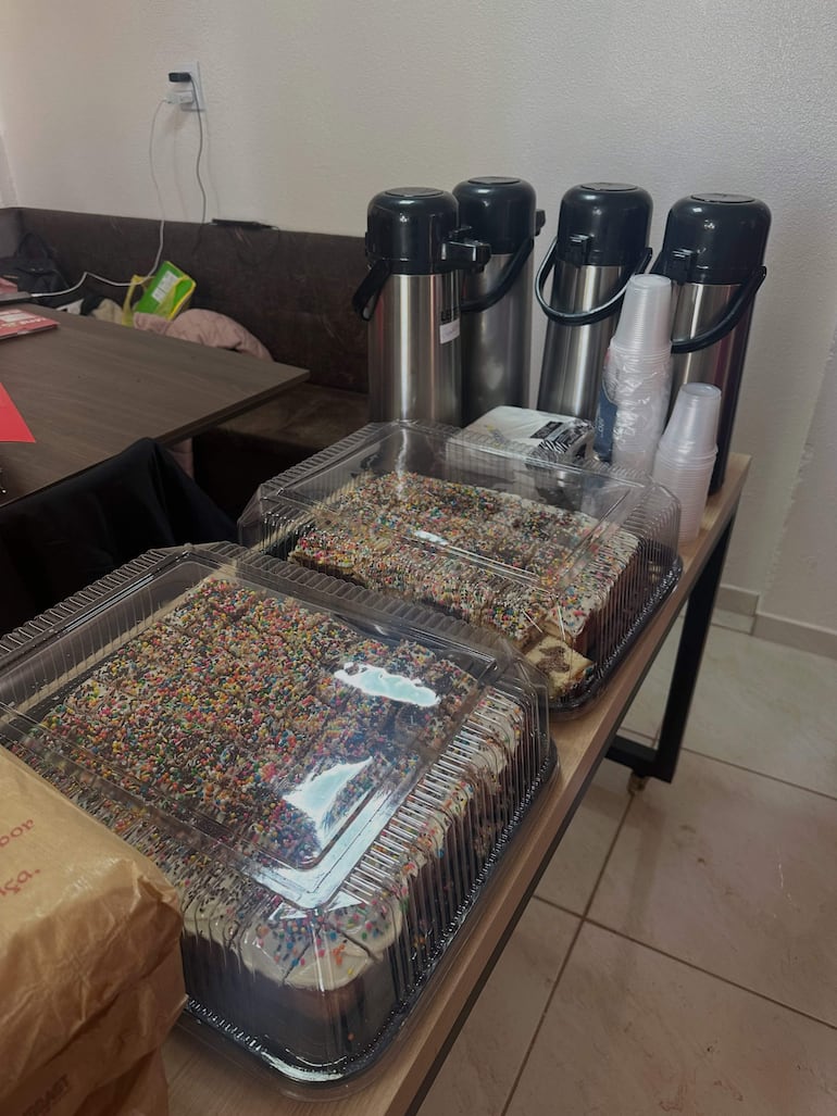 Mesa con pasteles decorados y termos de acero en un espacio interior claro y ordenado.