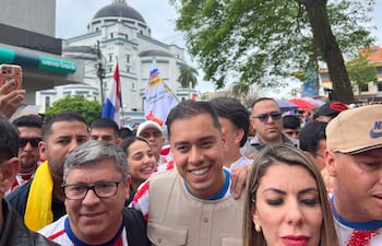 Grupo de personas sonrientes en manifestación, algunos con camisetas de colores patrióticos y banderas de Paraguay.