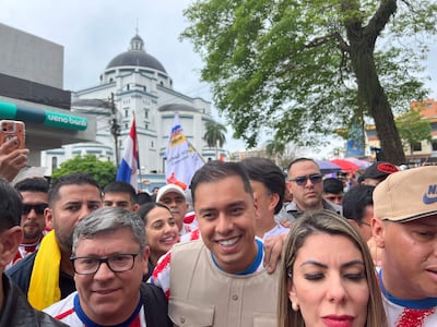 Grupo de personas sonrientes en manifestación, algunos con camisetas de colores patrióticos y banderas de Paraguay.