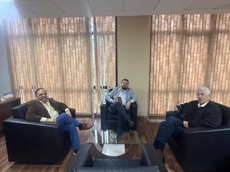 Arnoldo Wiens, Colym Soroka y Mario Varela conversan sentados en sillones negros, mostrando expresiones tranquilas y felices en un ambiente interior.