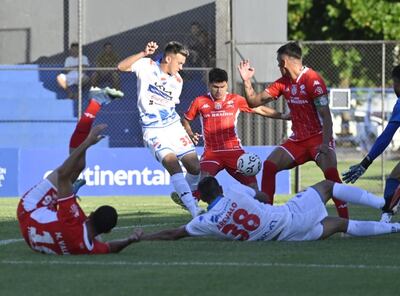 El delantero de Nacional, Nazareno Bazán, conecta el balón ante la presión de Miller Mareco.