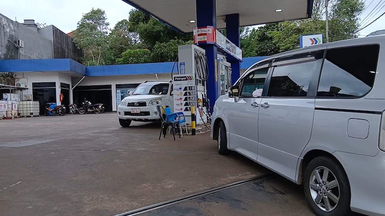 Cartel de precios de combustibles en la estación de servicio, con detalles sobre GLP y otros servicios, bajo un cielo nublado.
