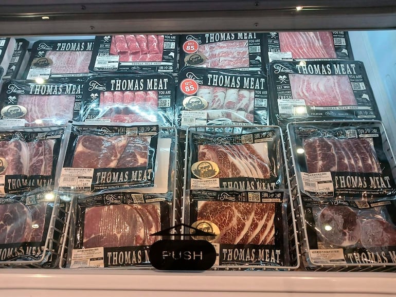 Congelador con paquetes de carne de THOMAS MEAT, mostrados en capas, con etiquetas de calidad premium visibles.