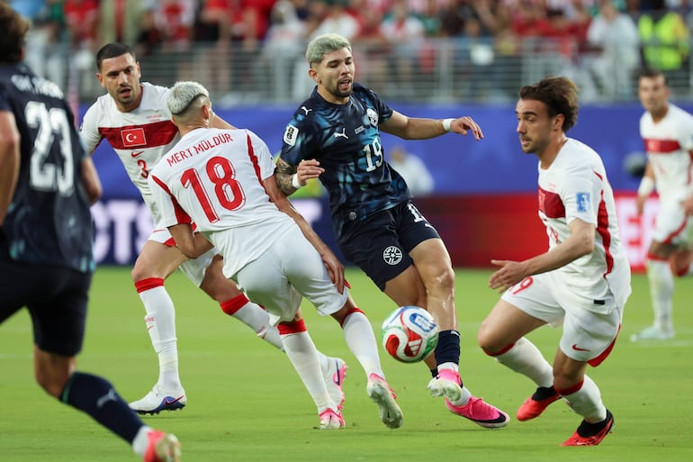 Mert Muldur (i) de Turquía disputa el balón con Julio Enciso (c) de Paraguay este viernes, en un partido del grupo D del Mundial de la FIFA 2026 entre Turquía y Paraguay, en el estadio Levi´s en Santa Clara (Estados Unidos).